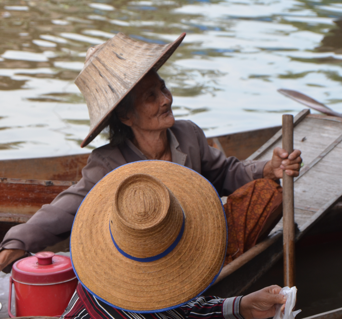 Commerçante au chapeau de paille sur une barque, marché flottant en Thaïlande